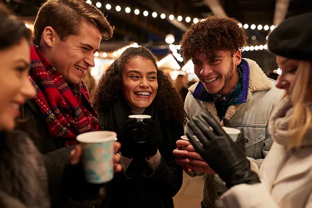 A multi-racial group of friends enjoying a drink at a Christmas market. 